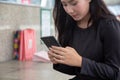 Beautiful girl using mobile phone at mallÃÂ with shopping bags in background..Asian young girl holding mobile phone makes purchases Royalty Free Stock Photo